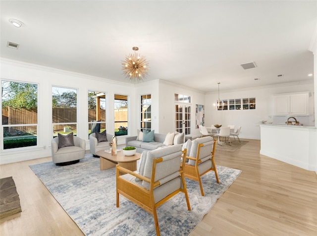 living room featuring a chandelier, light hardwood / wood-style floors, and crown molding