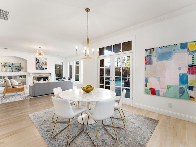 dining room with french doors, light hardwood / wood-style floors, a notable chandelier, and ornamental molding