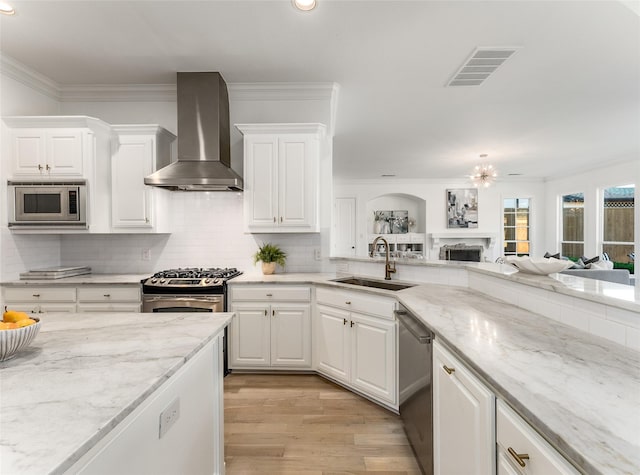 kitchen with sink, white cabinets, wall chimney range hood, and appliances with stainless steel finishes