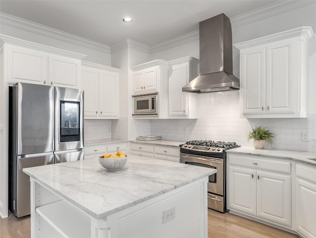 kitchen with white cabinets, wall chimney range hood, a kitchen island, light stone counters, and stainless steel appliances