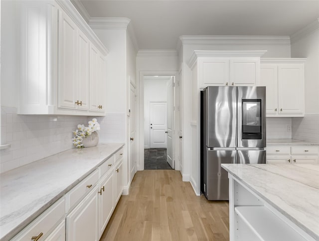 kitchen featuring stainless steel refrigerator, light stone countertops, decorative backsplash, white cabinets, and light wood-type flooring