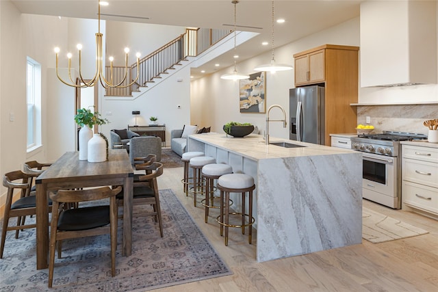 kitchen featuring hanging light fixtures, sink, stainless steel appliances, and a kitchen island with sink