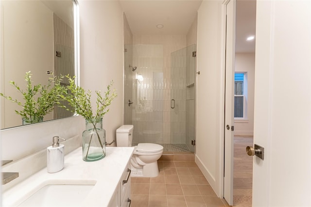 bathroom with tile patterned floors, vanity, a shower with shower door, and toilet