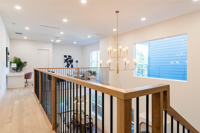 corridor featuring light wood-type flooring and an inviting chandelier