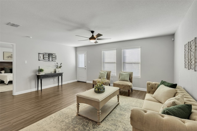 living room with a textured ceiling, dark hardwood / wood-style floors, and ceiling fan