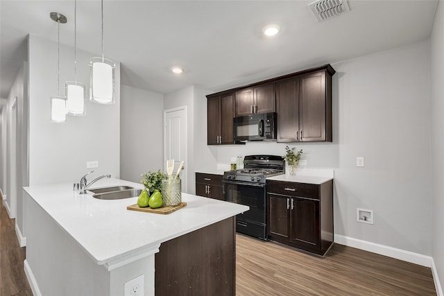 kitchen with dark brown cabinets, sink, black appliances, decorative light fixtures, and hardwood / wood-style flooring