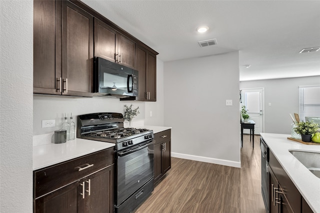 kitchen with black appliances, dark hardwood / wood-style floors, and dark brown cabinets