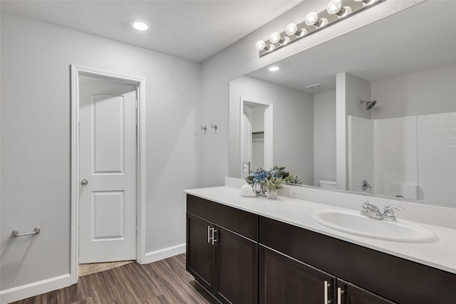 bathroom with a shower, hardwood / wood-style floors, vanity, and toilet