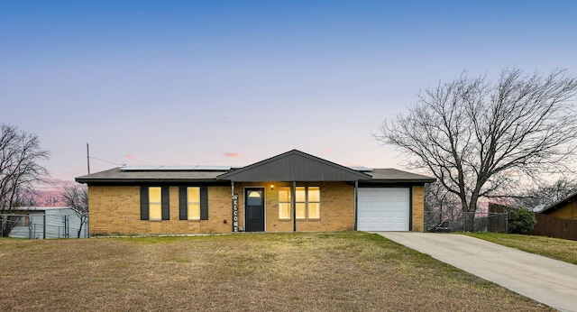 view of front of property featuring a garage, a lawn, and solar panels