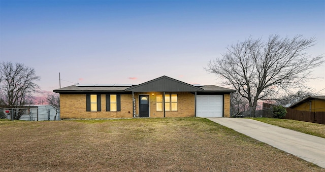 view of front of home featuring a garage, a yard, and solar panels