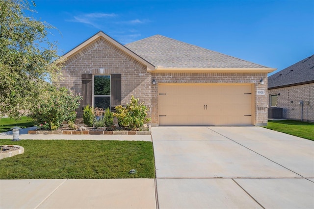 view of front of property featuring cooling unit, a front yard, and a garage