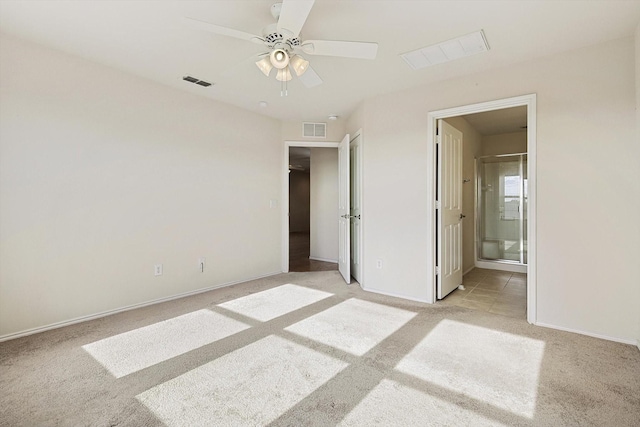 unfurnished bedroom with ceiling fan, light colored carpet, and ensuite bath