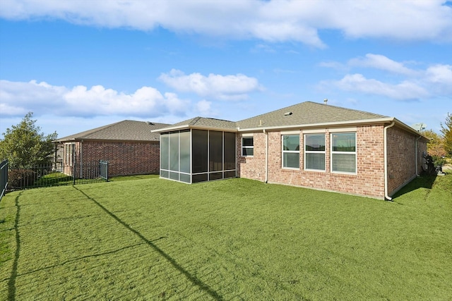 rear view of property featuring a yard and a sunroom