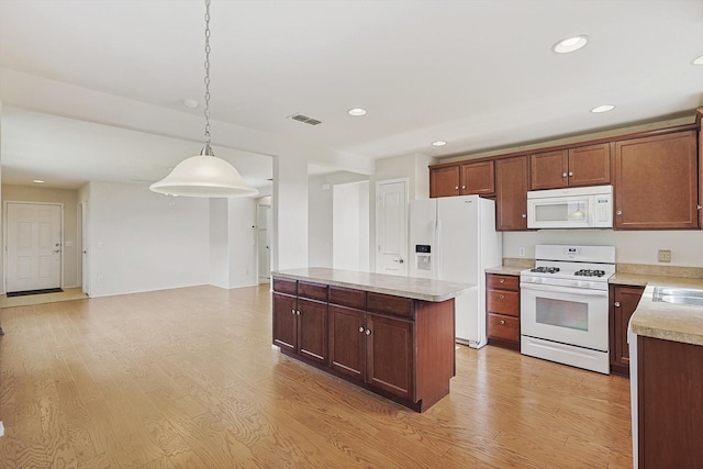 kitchen with white appliances, sink, decorative light fixtures, light hardwood / wood-style floors, and a kitchen island