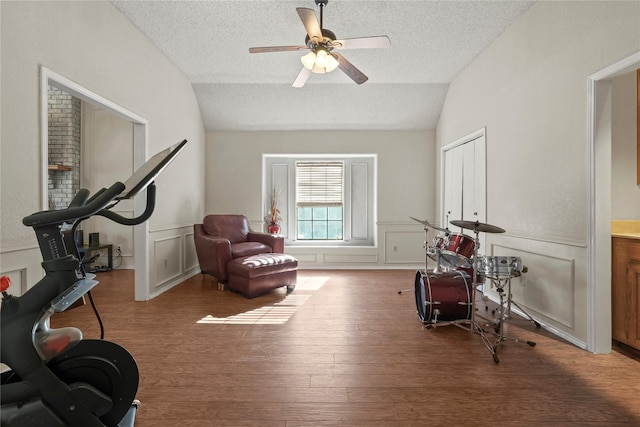 exercise area featuring hardwood / wood-style floors, ceiling fan, lofted ceiling, and a textured ceiling