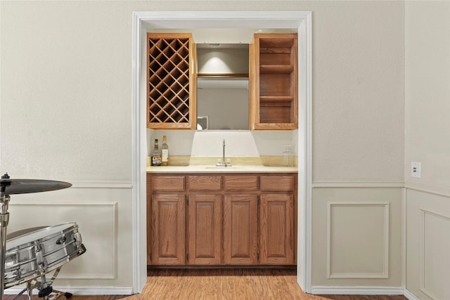 bar featuring sink and light hardwood / wood-style flooring