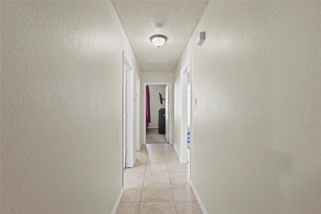 hall featuring light tile patterned floors and a textured ceiling