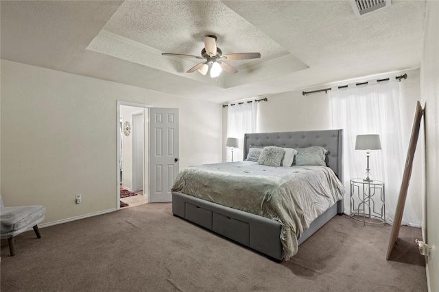 carpeted bedroom featuring a raised ceiling, ceiling fan, and a textured ceiling