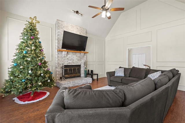 living room featuring ceiling fan, dark hardwood / wood-style flooring, lofted ceiling, and a brick fireplace