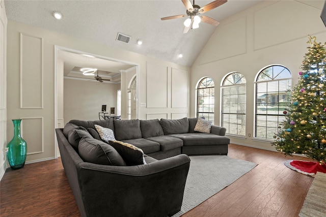 living room with ceiling fan, dark hardwood / wood-style flooring, a towering ceiling, and a textured ceiling