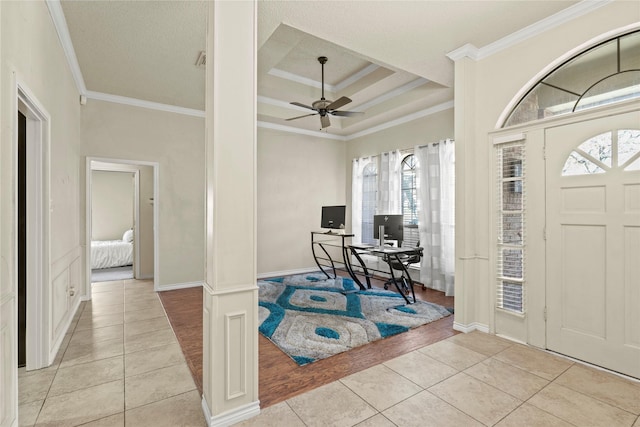 tiled entryway with ceiling fan, ornamental molding, and a tray ceiling