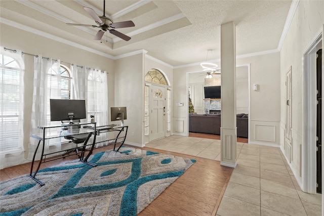 office area with a fireplace, light tile patterned floors, a raised ceiling, and ornamental molding