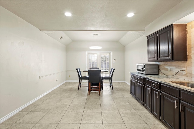 tiled dining room featuring lofted ceiling and sink