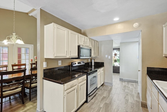 kitchen featuring stainless steel appliances, vaulted ceiling, pendant lighting, light hardwood / wood-style flooring, and white cabinets