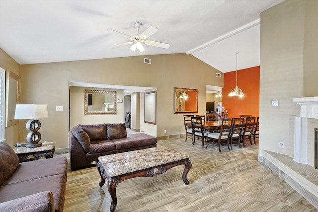 living room featuring ceiling fan with notable chandelier, light hardwood / wood-style flooring, and vaulted ceiling