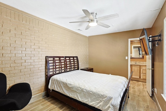 bedroom featuring light hardwood / wood-style flooring, ceiling fan, and brick wall