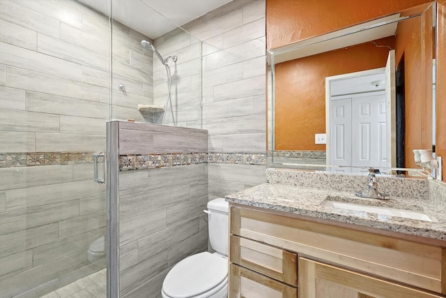 bathroom with vanity, an enclosed shower, tile walls, and toilet