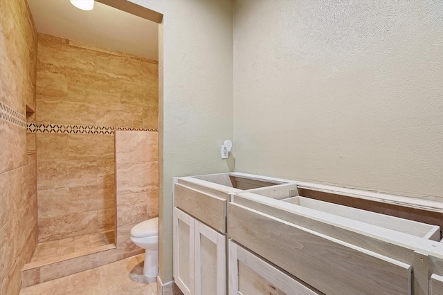 bathroom featuring tile patterned flooring, toilet, and a tile shower