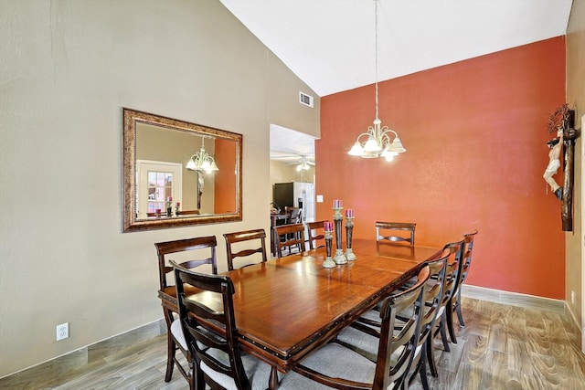 dining space with hardwood / wood-style floors, ceiling fan with notable chandelier, and lofted ceiling