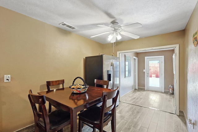 dining room featuring a textured ceiling, light hardwood / wood-style flooring, and ceiling fan