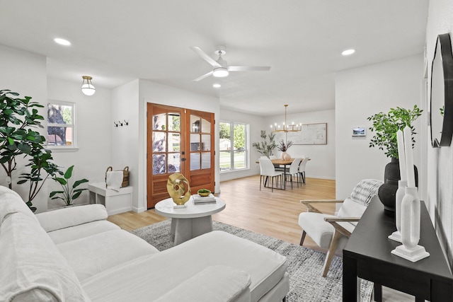 living room featuring french doors, light hardwood / wood-style floors, and ceiling fan with notable chandelier