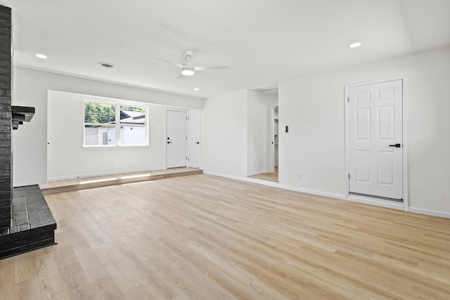 unfurnished living room with a brick fireplace, ceiling fan, and light wood-type flooring