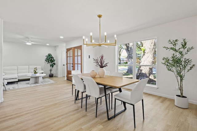 dining space with ceiling fan with notable chandelier and light wood-type flooring