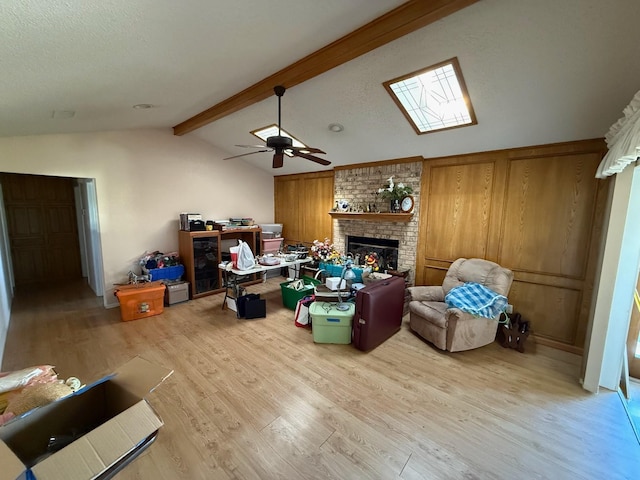 living room with lofted ceiling with beams, ceiling fan, a fireplace, and light hardwood / wood-style flooring