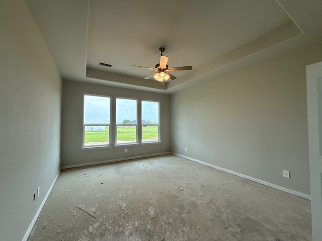 spare room featuring a ceiling fan, visible vents, a raised ceiling, and baseboards