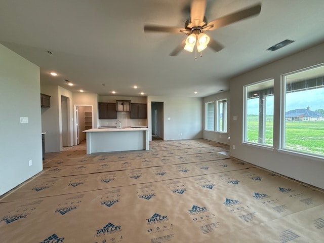 unfurnished living room with a sink, recessed lighting, ceiling fan, and visible vents