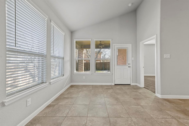 tiled empty room featuring vaulted ceiling