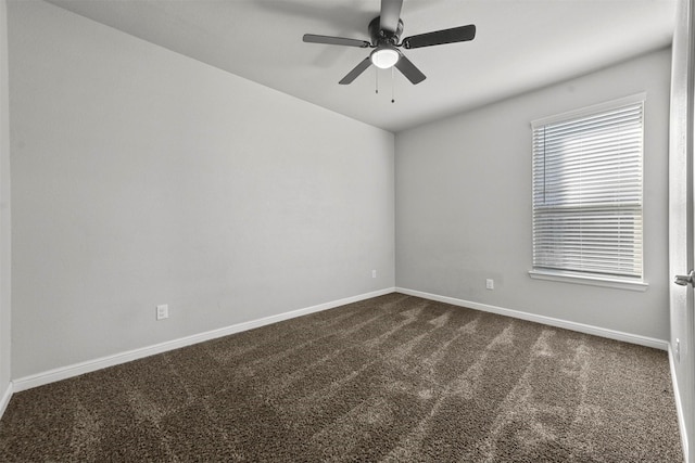 spare room featuring dark colored carpet and ceiling fan