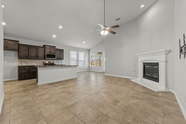 kitchen featuring dark brown cabinetry, ceiling fan, stainless steel appliances, tasteful backsplash, and light tile patterned floors