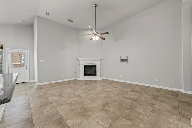 unfurnished living room with ceiling fan and high vaulted ceiling