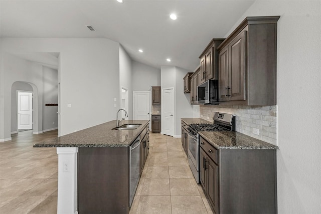 kitchen featuring sink, dark stone countertops, tasteful backsplash, dark brown cabinetry, and stainless steel appliances