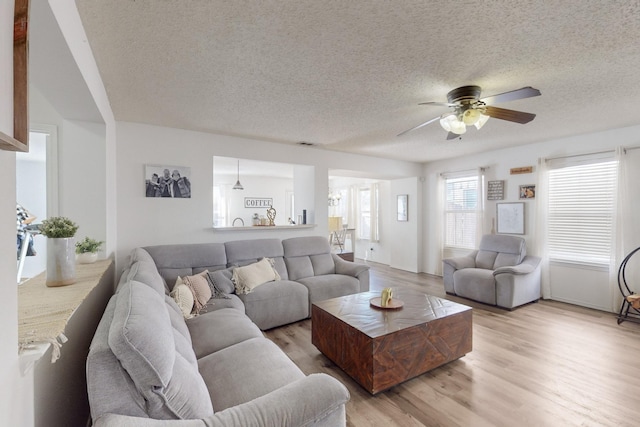 living room with ceiling fan, a textured ceiling, and light hardwood / wood-style floors