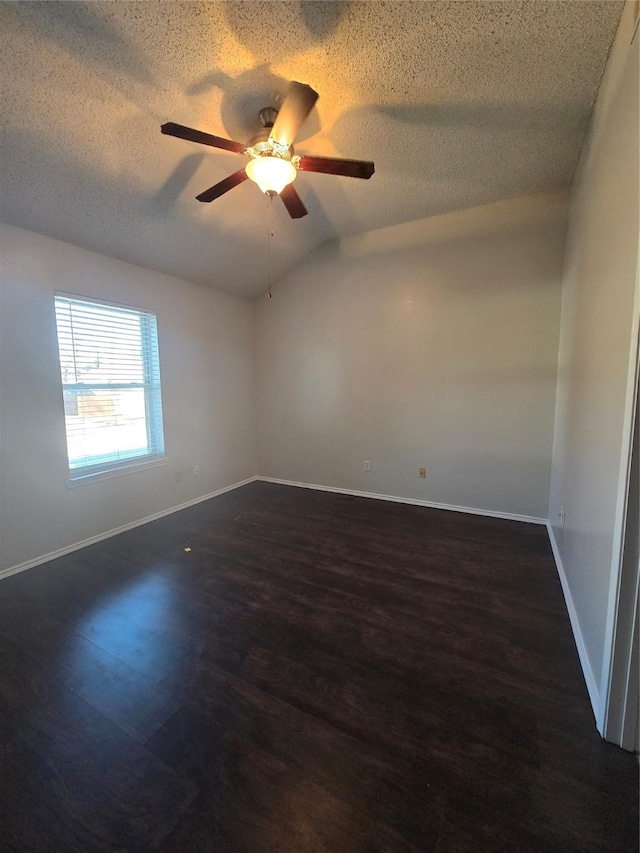 empty room with a textured ceiling, ceiling fan, dark hardwood / wood-style floors, and lofted ceiling