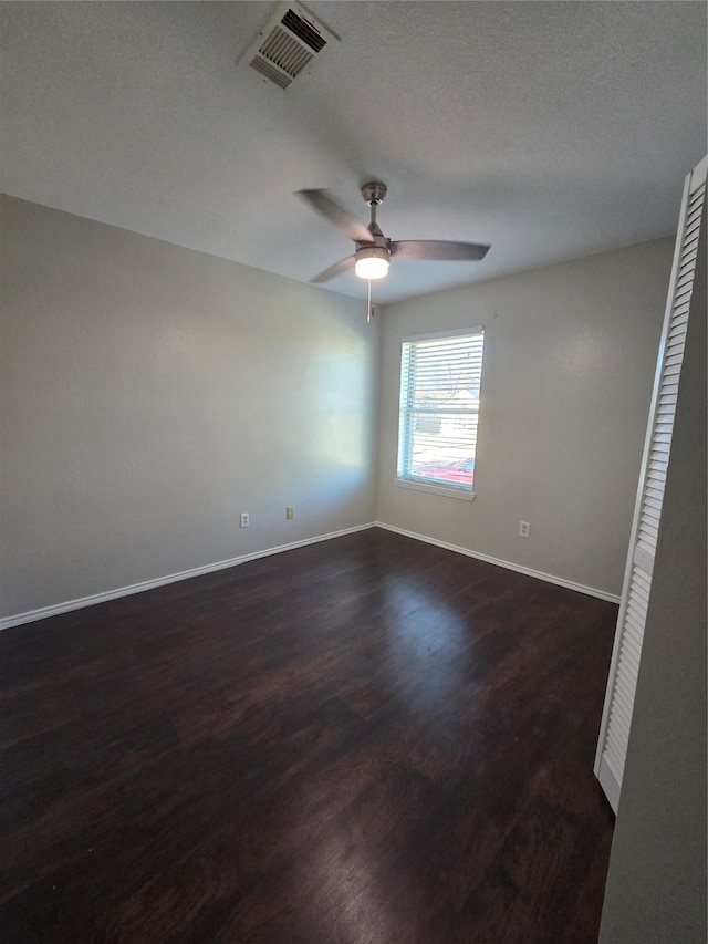 empty room with ceiling fan, dark hardwood / wood-style flooring, and a textured ceiling