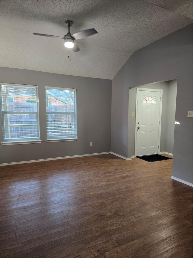 foyer with a textured ceiling, ceiling fan, dark hardwood / wood-style floors, and vaulted ceiling