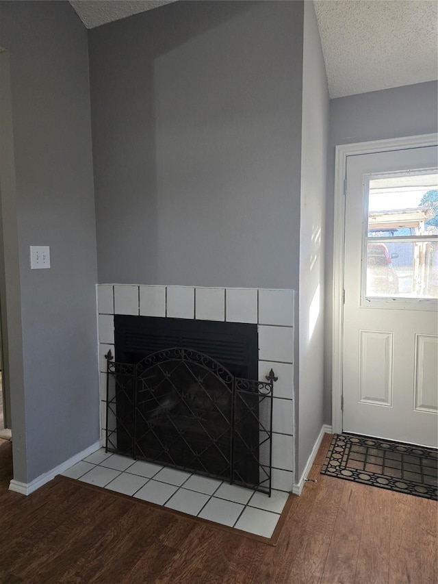 interior details featuring wood-type flooring, a textured ceiling, and a tile fireplace